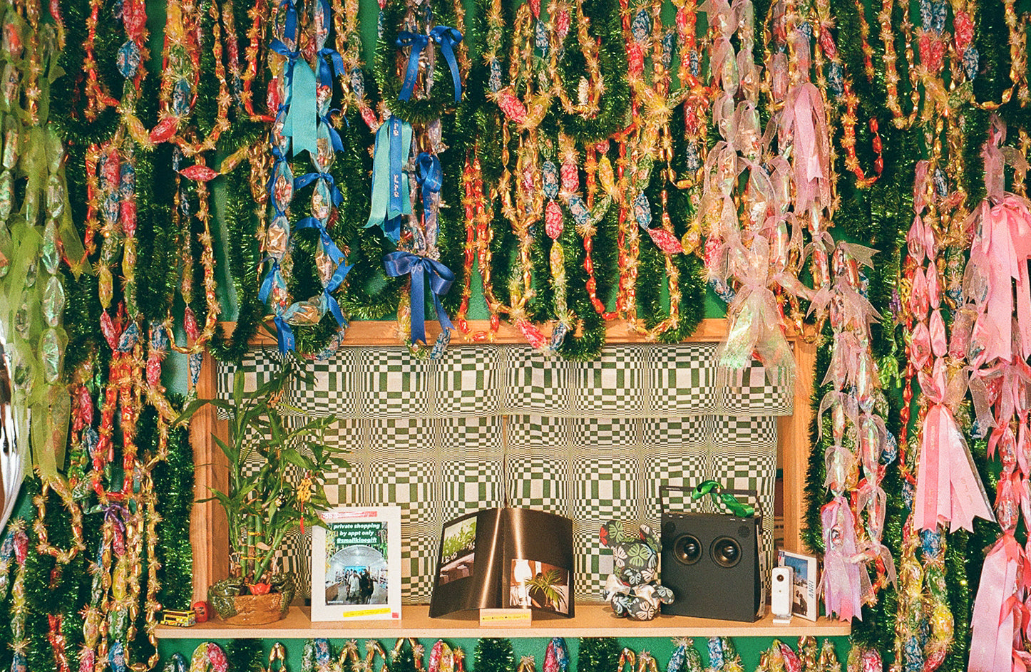 Decorative wall with candy lei, ribbons, and a patterned curtains.